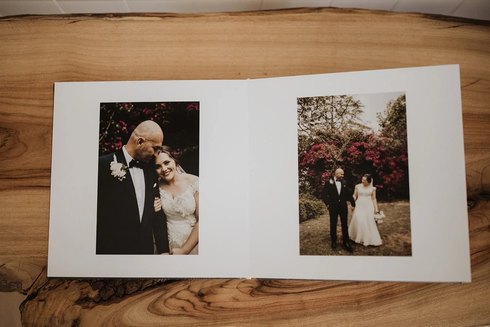An open wedding album on a timber table, a portrait on each page