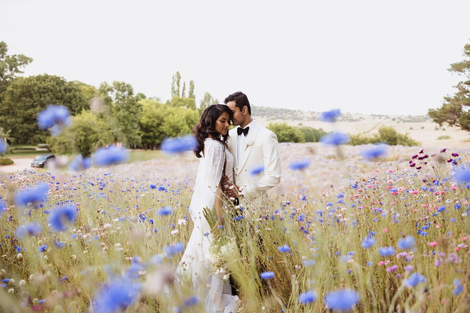 A couple close together in a field of blue cornflowers