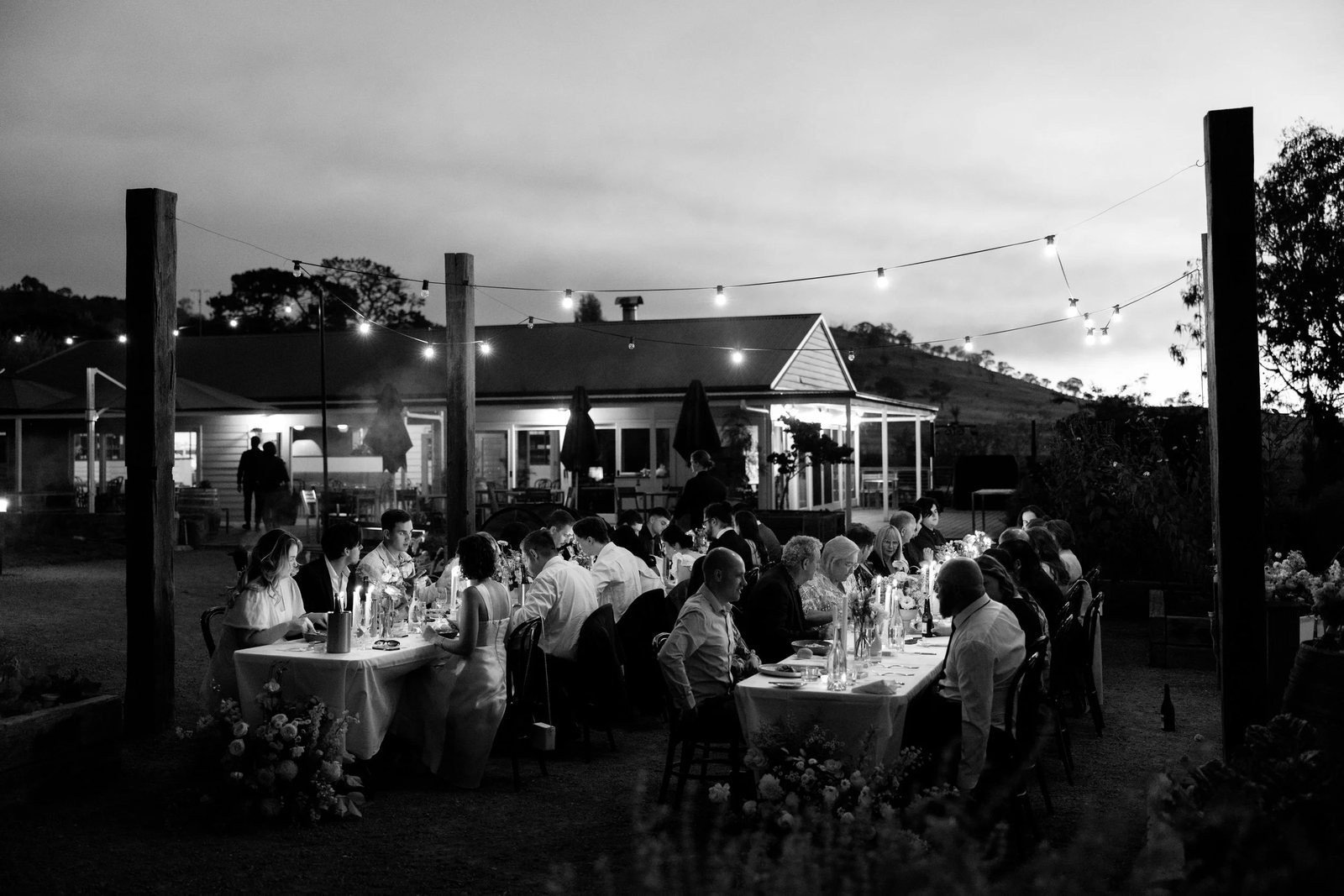 Black and white: an outdoor reception at dusk under festoon lights