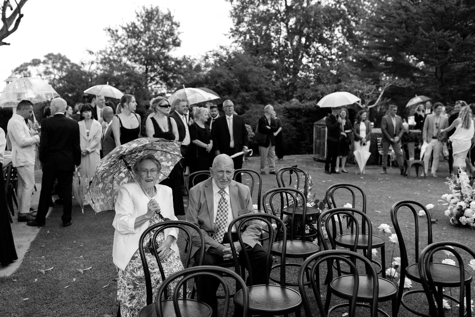Black and white: guests in their seats under parasols at an outdoor ceremony